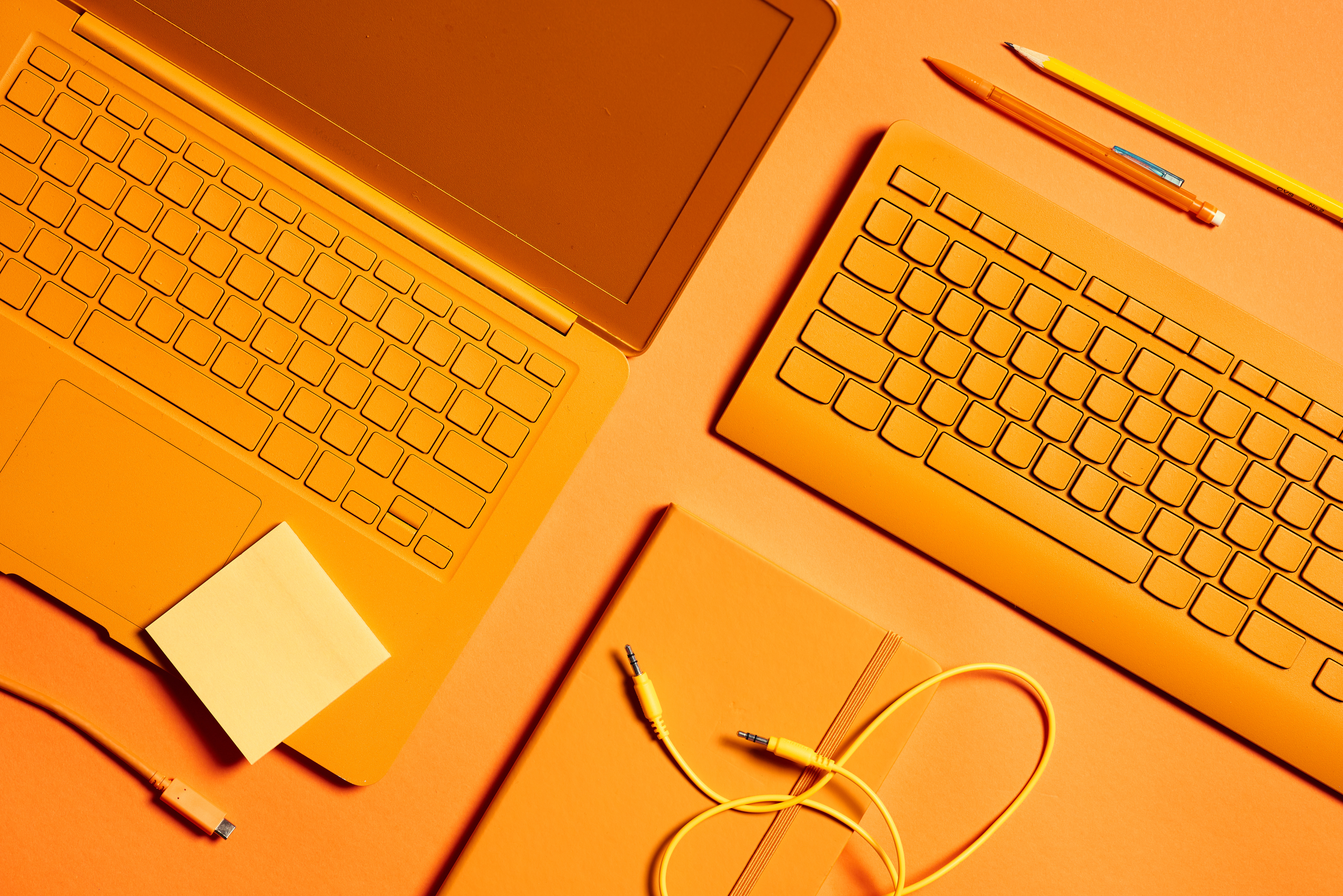 flat lay image of desk set up including laptop, charging cables, pens, and more