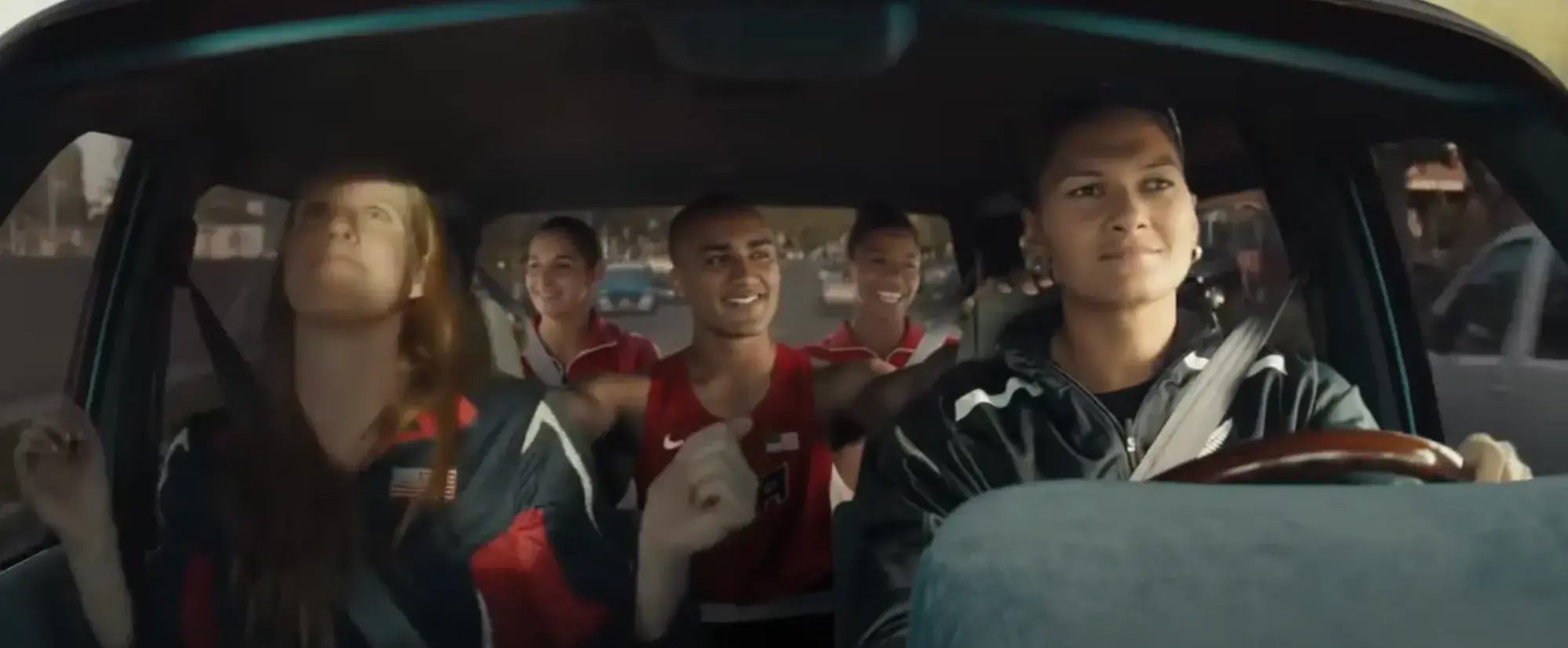 Screencap from advertisement. Five Olympic athletes on a car road trip.