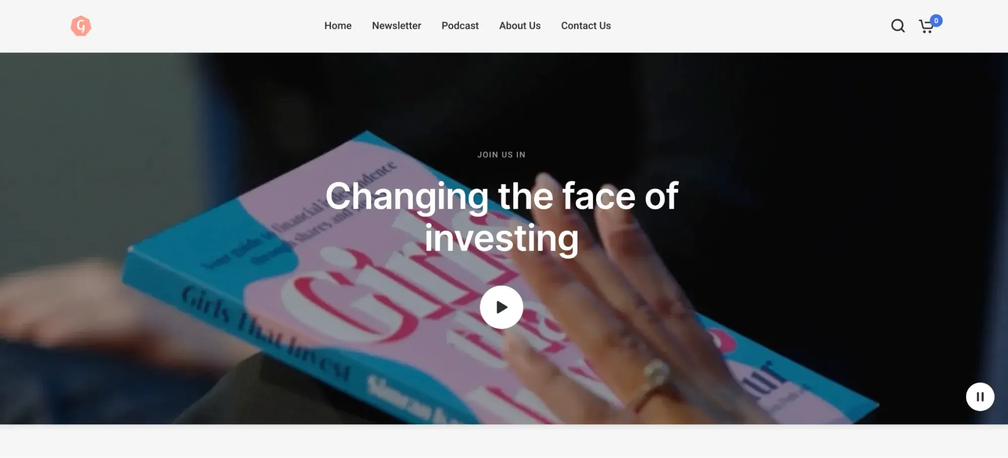 Website header for a company named Girls That Invest. It shows a hand holding a book titled “Girls That Invest” with text overlaid saying “Changing the face of investing” and a play button.