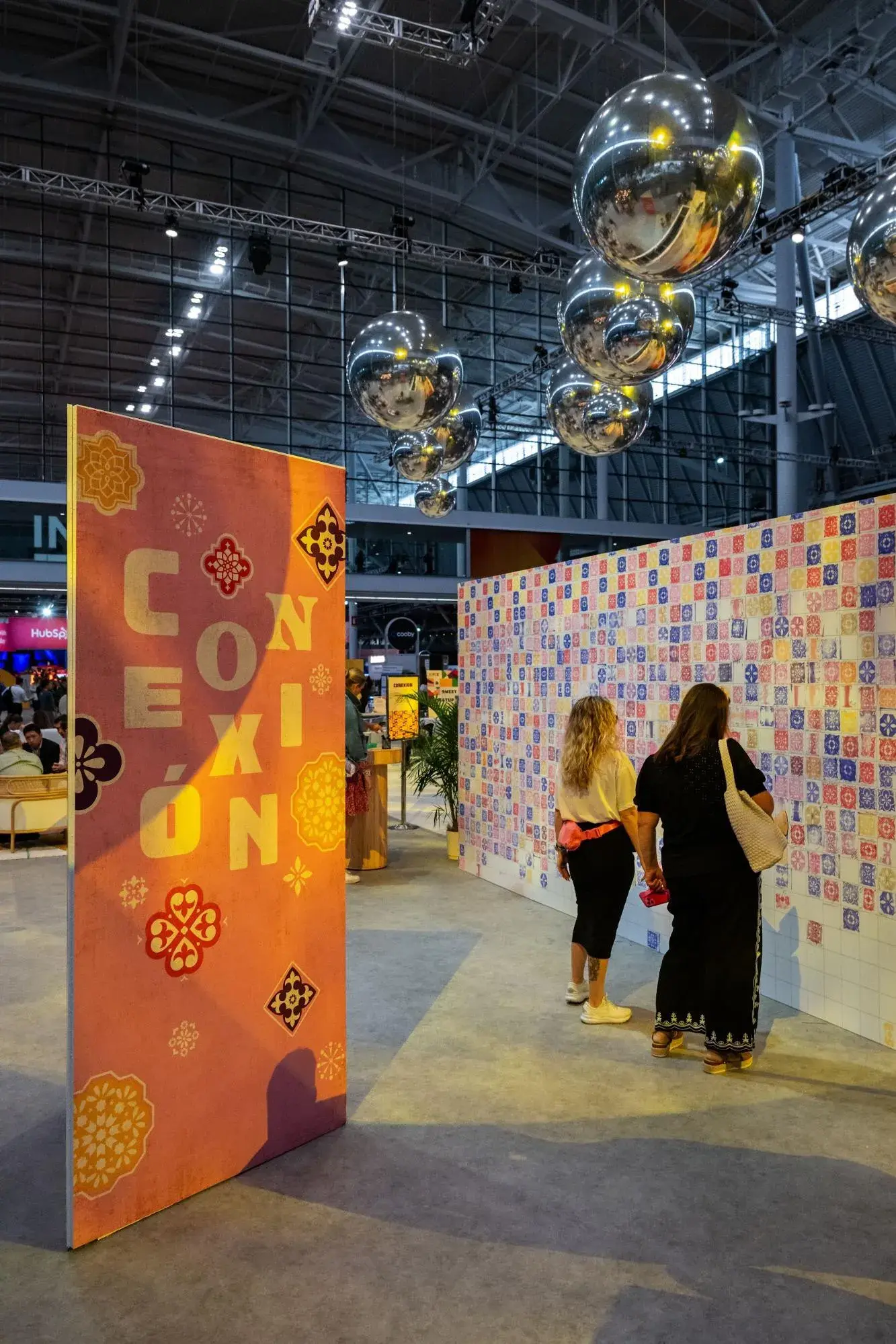 Two attendees at INBOUND 2024 look at a Conexión display