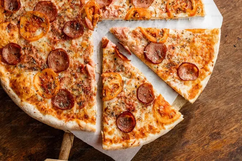 Two cut pizza slices with pepperoni and tomato toppings